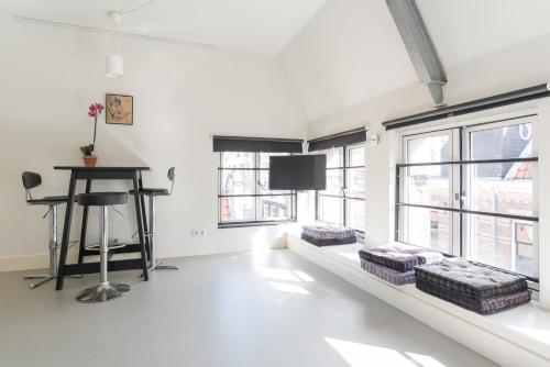 a white living room with a table and windows at Tweede Laurierdwarsstraat Apartment in Amsterdam