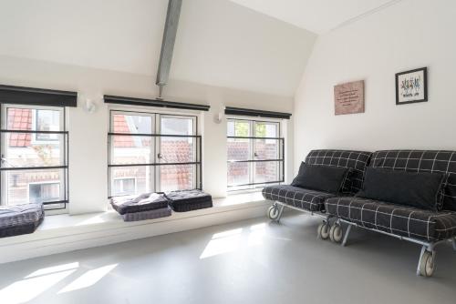 a living room with a couch and some windows at Tweede Laurierdwarsstraat Apartment in Amsterdam