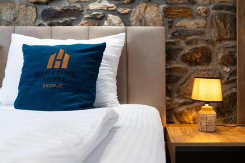 a bed with a blue pillow and a table with a lamp at Old Stone Hotel Skopje in Skopje