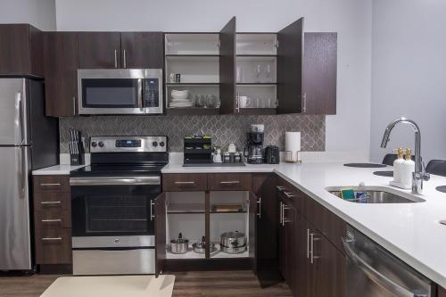 a kitchen with stainless steel appliances and wooden cabinets at Modern King Suite Downtown Walkable Pool & Gym in Wilmington