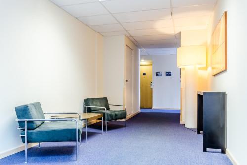 a waiting room with chairs and a table and a door at Hotel YIT Ciudad De Zaragoza in Zaragoza