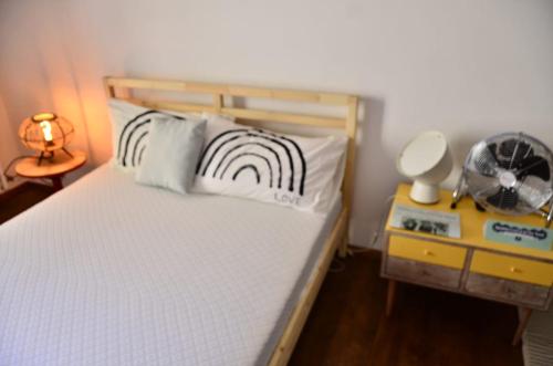 a bed with two pillows and a night stand with a lamp at LIBERA IDEA Art run space in Civitanova Alta