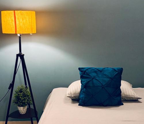 a bed with a blue pillow next to a lamp at Upaja Ghar Homestay in Guwahati