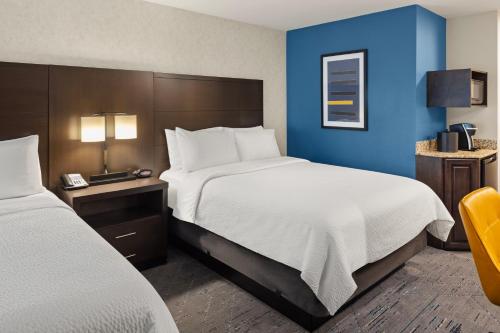 a hotel room with two beds and a blue wall at Holiday Inn Express Moline - Quad Cities Area by IHG in Moline
