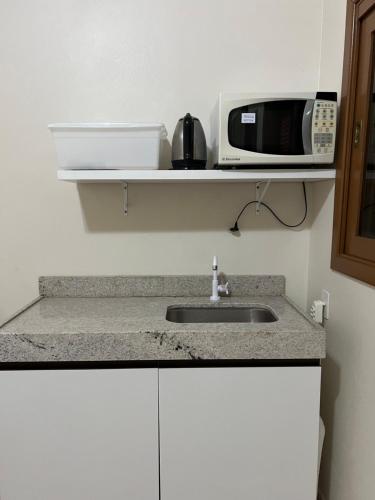 a kitchen with a sink and a microwave at Suíte privativa in Novo Hamburgo
