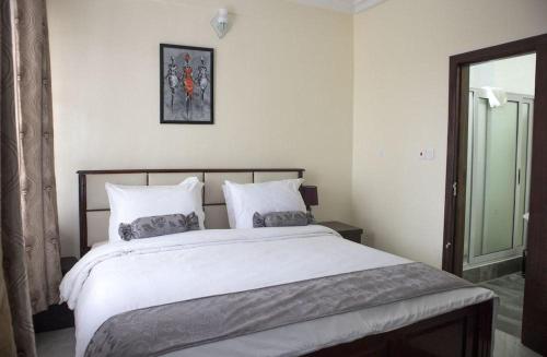a bedroom with a large bed with white sheets and pillows at Villa Angelia Hotel in Accra