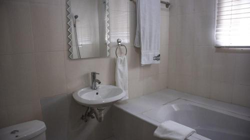a bathroom with a sink and a tub and a toilet at Villa Angelia Hotel in Accra