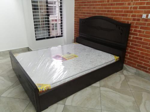 Ein Bett steht in einem Zimmer neben einer Backsteinmauer. in der Unterkunft The Abode- SUST Gate in Sylhet