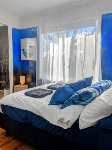 a bedroom with blue walls and a large bed with blue pillows at Blue Mountains Urban Farm Stay near Sydney in Hazelbrook