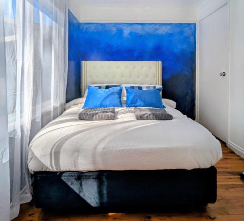 a bedroom with blue walls and a bed with blue pillows at Blue Mountains Urban Farm Stay near Sydney in Hazelbrook