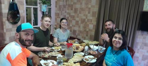 a group of people sitting around a table eating food at Guesthouse Irina Family Hotel in Tsvirmi