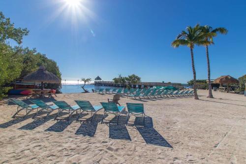 a group of chairs on a beach with the sun at Luxurious 2BR 2BA Ocean Pointe Condo Tavernier Fl in Tavernier
