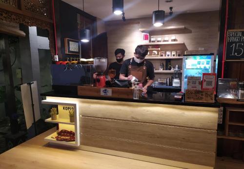 two men are preparing food at a counter in a restaurant at Omah Nayan Guest House in Seturan