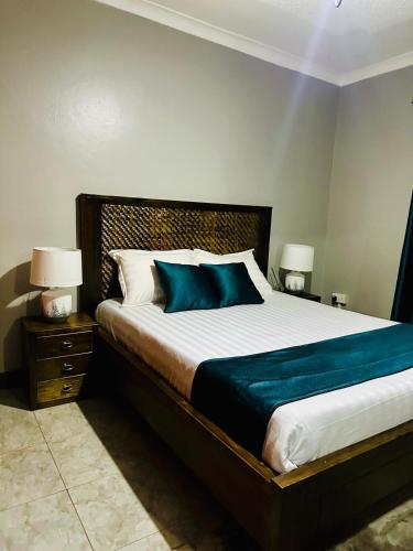 a bedroom with a large bed with blue pillows at Kylo cozy calm in Kampala