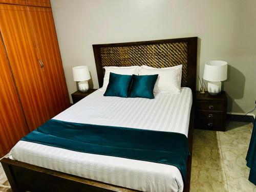 a bedroom with a large bed with blue pillows at Kylo cozy calm in Kampala