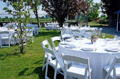 un tavolo apparecchiato per un matrimonio con tavoli e sedie bianchi di Agriturismo AgriTexS a Savigliano