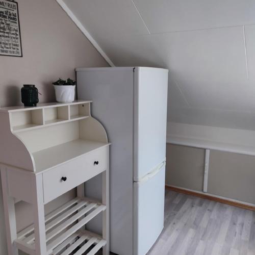 a white refrigerator in a room with a shelf at Loft apartment in the heart of Hamar in Hamar