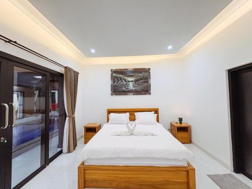 a white bedroom with a bed and a window at MeyGun House in Lovina