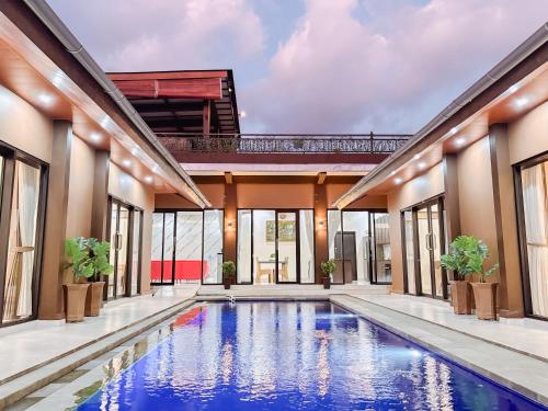 an indoor swimming pool in a house with windows at MeyGun House in Lovina