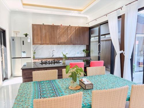 a dining room with a table and chairs and a kitchen at MeyGun House in Lovina