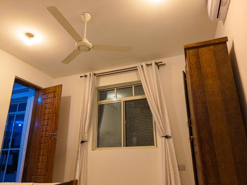 a ceiling fan and a window in a room at Beachfront Bliss Zanzibar - Stylish 1BR Oceanview Apartment in Uroa in Uroa
