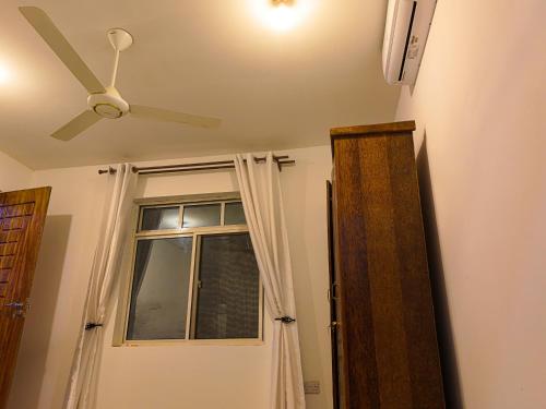 a ceiling fan and a door with a window at Beachfront Bliss Zanzibar - Stylish 1BR Oceanview Apartment in Uroa in Uroa