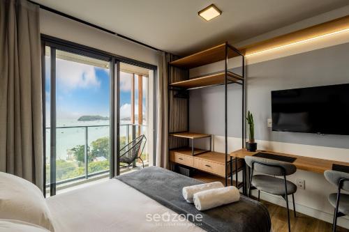 a bedroom with a bed and a desk and a large window at Estúdios c/ Vista Frente Mar no Penha Spot | PSO - VF in Gravata