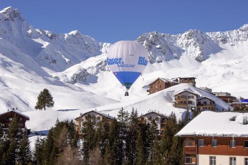 a hot air balloon flying over a snow covered mountain at Viktoria A12 by Arosa Vacations, Renoviertes App mit Bergblick im Zentrum in Arosa
