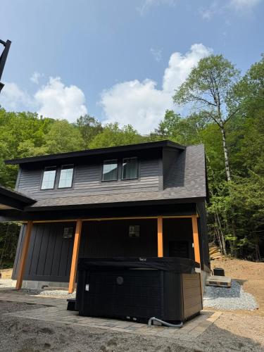 a black house with a garage at NEW Skye Ridge Carriage House with Hot Tub in Killington