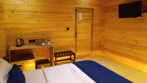 a bedroom with a bed and a desk and a television at Wood Chalets Ella in Ella