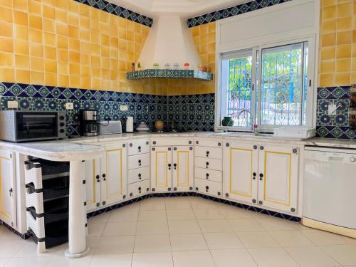 a kitchen with white cabinets and yellow tiles at Sidi Bou Said-style villa with pool in Hammamet