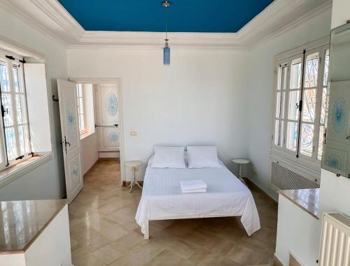 a white room with a bed and a blue ceiling at Sidi Bou Said-style villa with pool in Hammamet