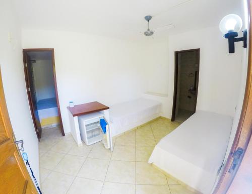 a room with two beds and a table in it at Pousada Cabo Frio in Cabo Frio