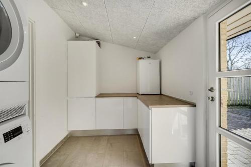a kitchen with white cabinets and a refrigerator at A house close to LEGO house in Billund