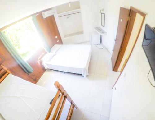 a small room with a bed and a window at Pousada Cabo Frio in Cabo Frio