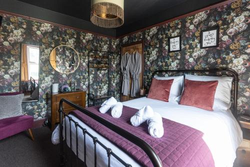 - une chambre avec un grand lit et du papier peint floral dans l'établissement Hopewell - Unique Rooms in the heart of Cliftonville, à Margate
