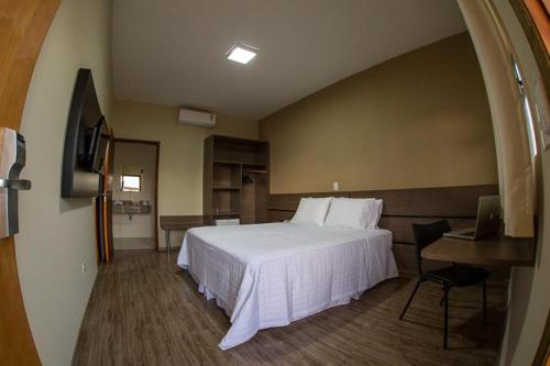 a hotel room with a bed and a desk at Decio Hotel - Presidente Venceslau Antigo KHotel in Presidente Venceslau
