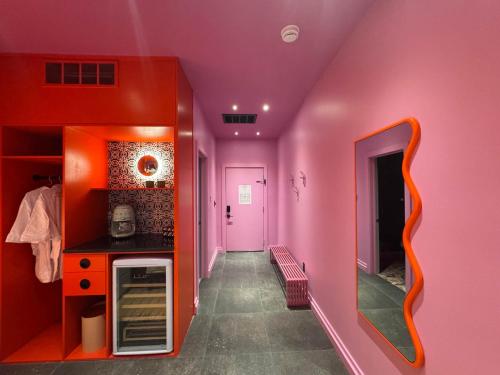 a hallway with pink walls and a mirror at Hotel Hilo - Room 202 in Louisville