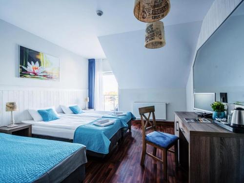 a hotel room with two beds and a television at Ach Mazury in Mikołajki