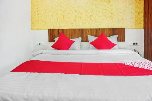a bedroom with a large bed with red pillows at Hotel O CeeRock in Bhopal