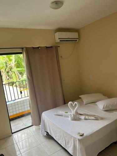 a bedroom with a white bed with a window at Pousada Corais in Ubatuba