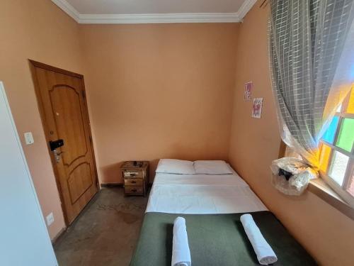 a small bedroom with two beds and a window at Lindo flat Serro Estilo Europeu Vila Rica Pampulha in Venda Nova