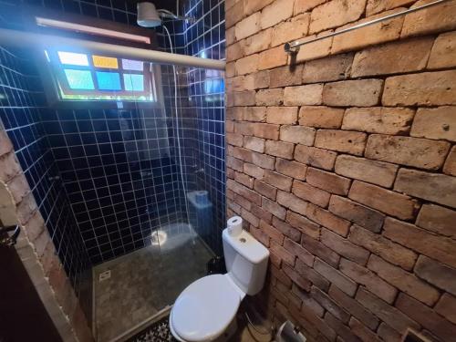 a bathroom with a toilet and a brick wall at Lindo flat Serro Estilo Europeu Vila Rica Pampulha in Venda Nova