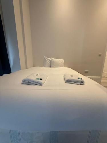 a large white bed with two towels on it at Cavendish Place Apartments in Eastbourne
