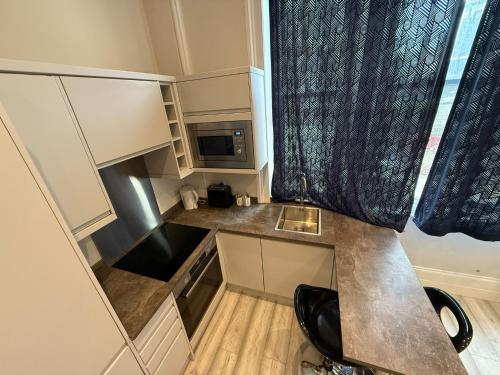a small kitchen with a sink and a microwave at Cavendish Place Apartments in Eastbourne