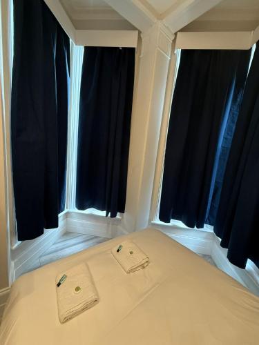 a bed in a room with two large windows at Cavendish Place Apartments in Eastbourne