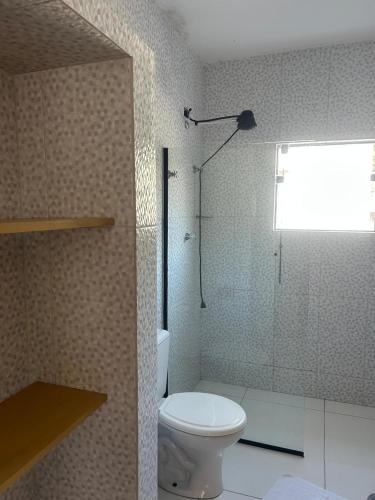 a bathroom with a toilet and a glass shower at Pousada Corais in Ubatuba