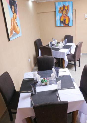 a dining room with tables and chairs and a painting at ebc lodge in Ndola