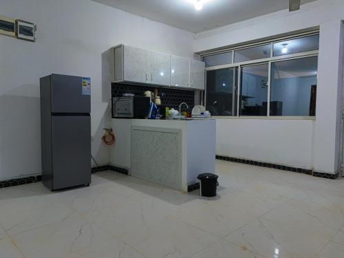 an empty kitchen with a refrigerator and a window at Beachfront Bliss Zanzibar - Stylish 1BR Oceanview Apartment in Uroa in Uroa