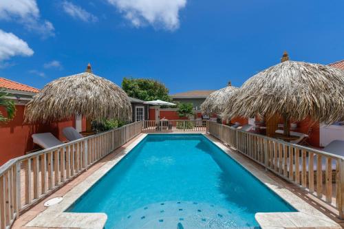 a swimming pool with chairs and umbrellas at Moderne Studio Sea dichtbij de zee met zwembad in Oranjestad